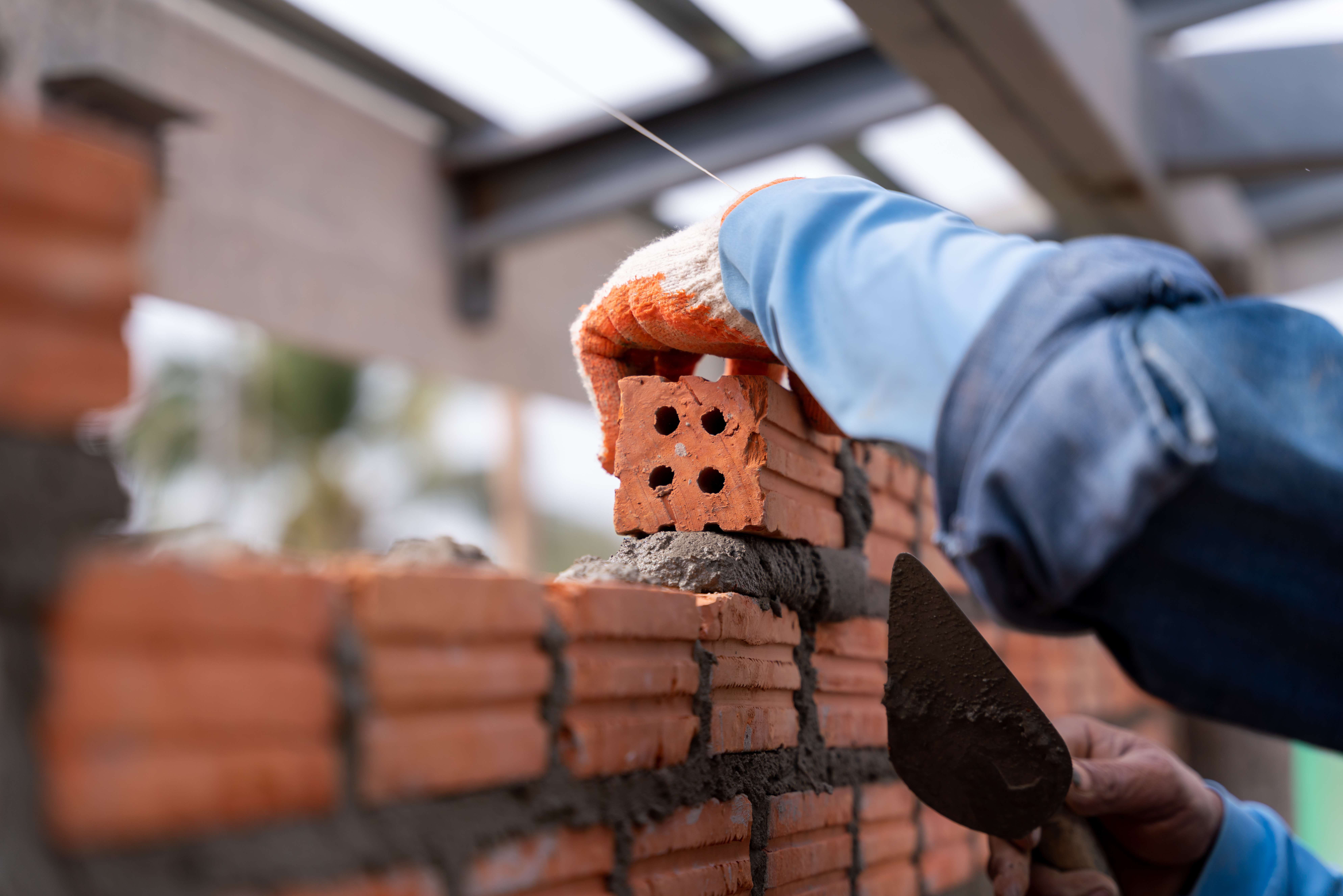 Close up of Bricklayer worker installing brick masonry on exteri